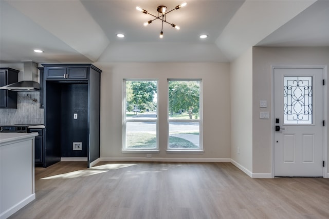 kitchen with wall chimney range hood, hardwood / wood-style flooring, and vaulted ceiling