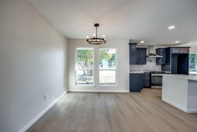 kitchen featuring wall chimney range hood, light stone countertops, light hardwood / wood-style flooring, and electric range