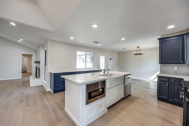 kitchen featuring lofted ceiling, sink, a center island with sink, stainless steel dishwasher, and light wood-type flooring