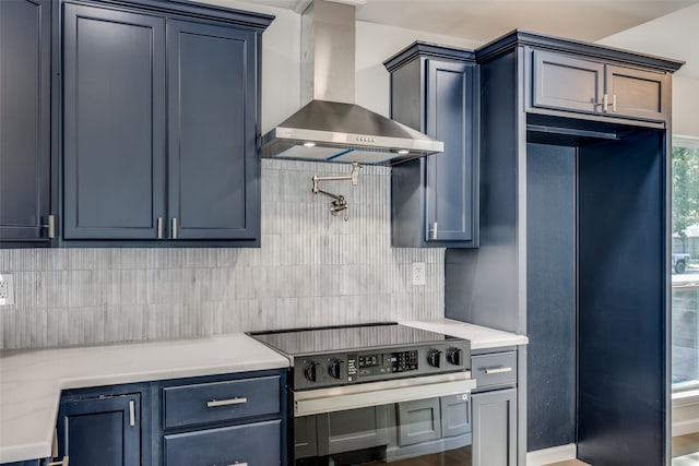 kitchen featuring light stone countertops, stainless steel range with electric stovetop, wall chimney exhaust hood, and decorative backsplash