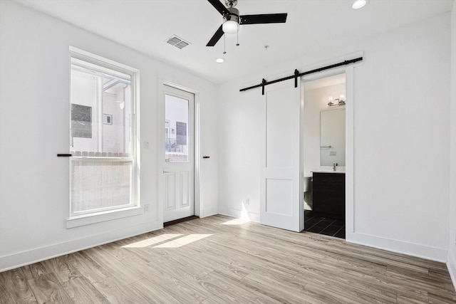 foyer entrance featuring light wood-type flooring, a barn door, and ceiling fan