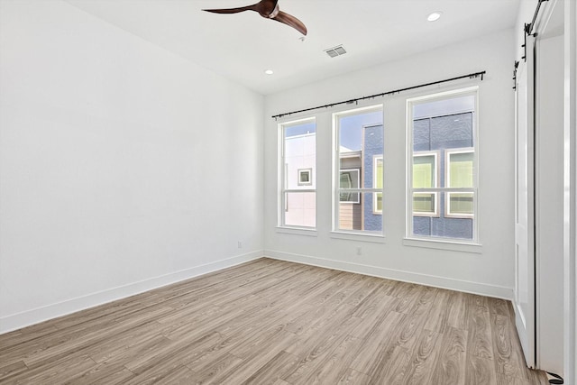 unfurnished room with a barn door, baseboards, ceiling fan, light wood-style floors, and recessed lighting