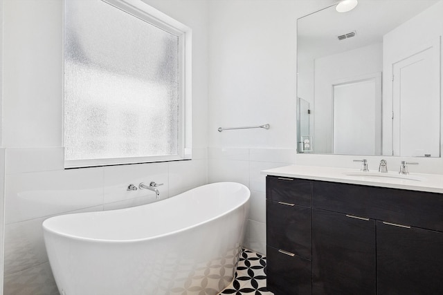 bathroom featuring vanity, a bath, and tile walls