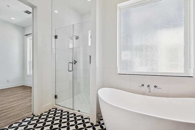 full bath featuring a stall shower, a wealth of natural light, visible vents, and a freestanding bath