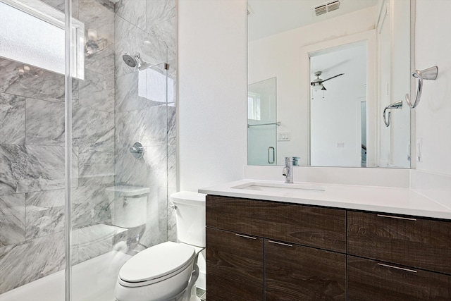 bathroom featuring vanity, toilet, ceiling fan, and a shower with shower door