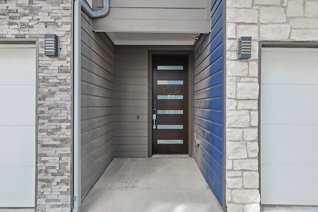 view of exterior entry with a garage and stone siding