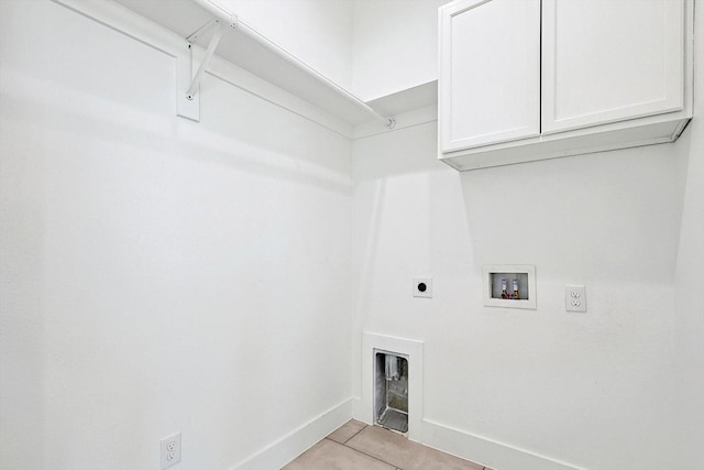 clothes washing area featuring washer hookup, cabinet space, light tile patterned flooring, electric dryer hookup, and baseboards