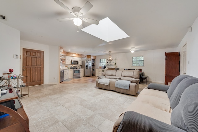 living room with ceiling fan and a skylight