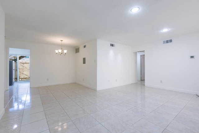 spare room with light tile patterned floors and an inviting chandelier