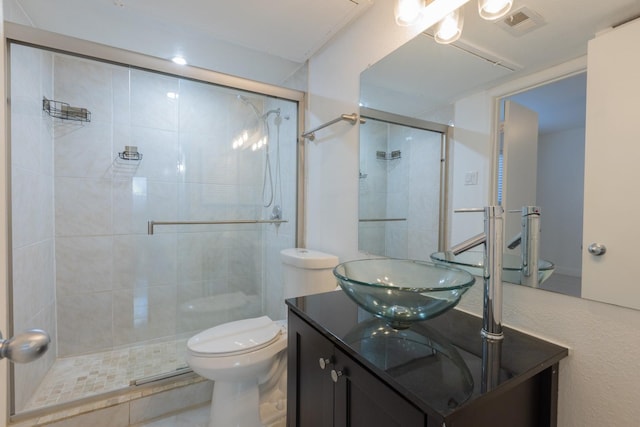 bathroom with vanity, a shower with shower door, and toilet