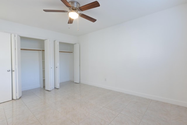 unfurnished bedroom featuring ceiling fan and multiple closets