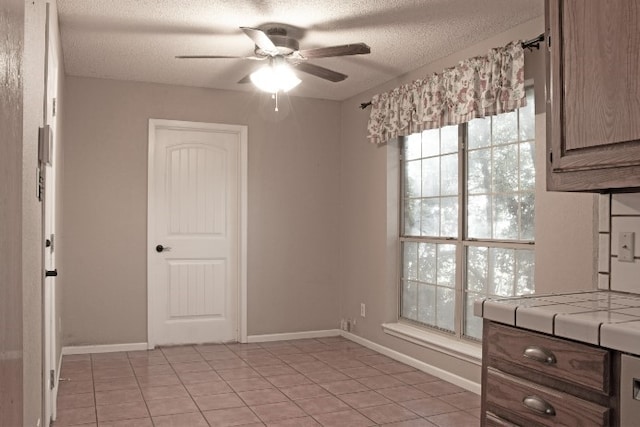 interior space with ceiling fan, light tile patterned floors, and a textured ceiling