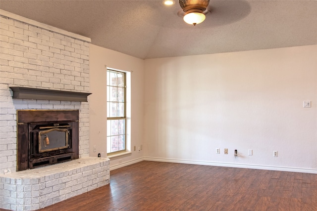 unfurnished living room with a wood stove, ceiling fan, dark hardwood / wood-style floors, vaulted ceiling, and a textured ceiling