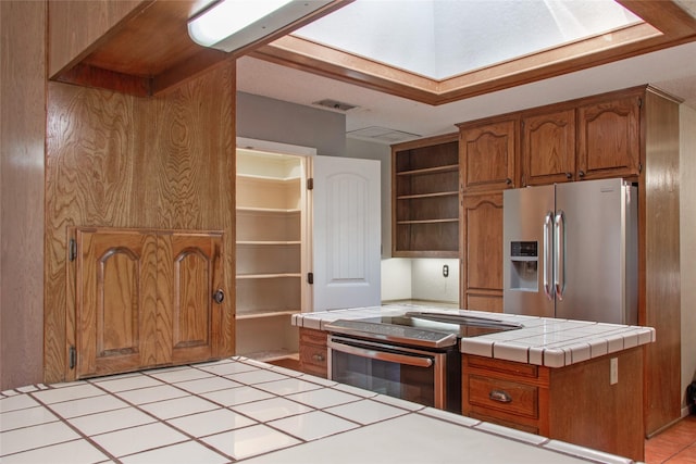 kitchen featuring stainless steel appliances, tile counters, and kitchen peninsula