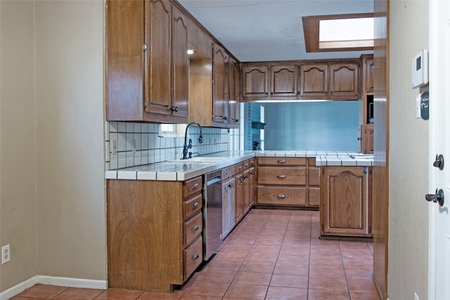 kitchen with dishwasher, sink, decorative backsplash, tile counters, and light tile patterned floors