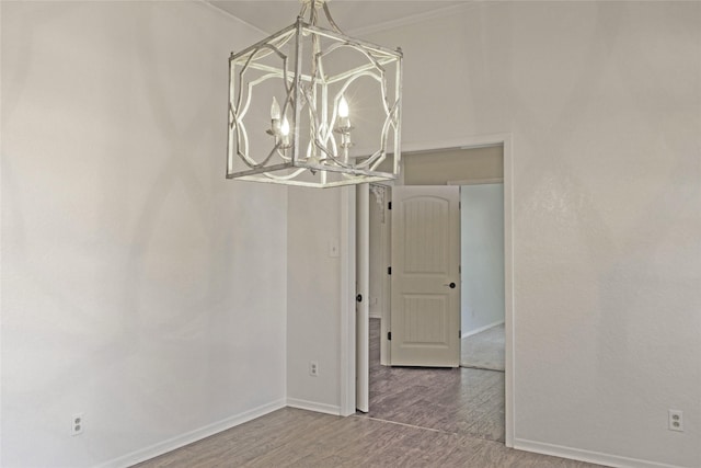 unfurnished dining area featuring ornamental molding, a notable chandelier, and hardwood / wood-style flooring