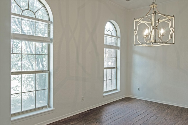 spare room featuring ornamental molding, plenty of natural light, dark hardwood / wood-style floors, and an inviting chandelier