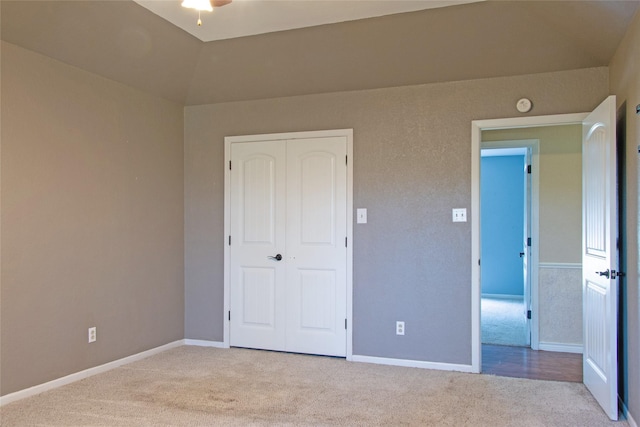 unfurnished bedroom with vaulted ceiling, light carpet, and a closet