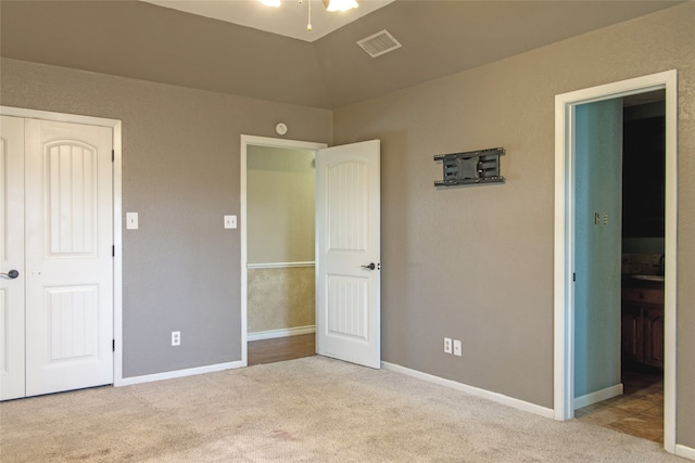 unfurnished bedroom with light carpet and lofted ceiling