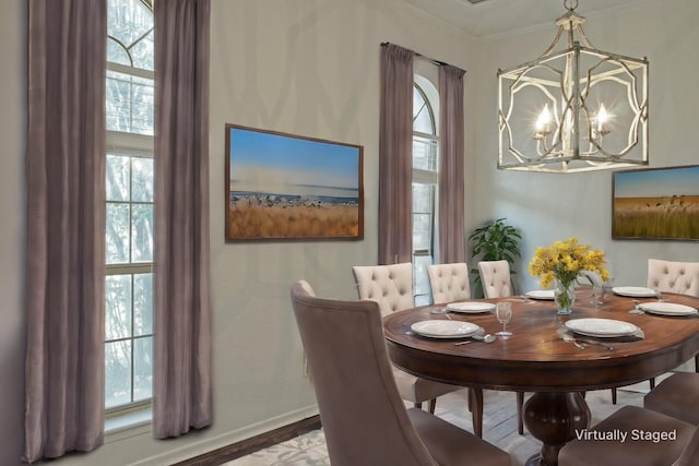 dining room with hardwood / wood-style flooring, ornamental molding, a wealth of natural light, and an inviting chandelier