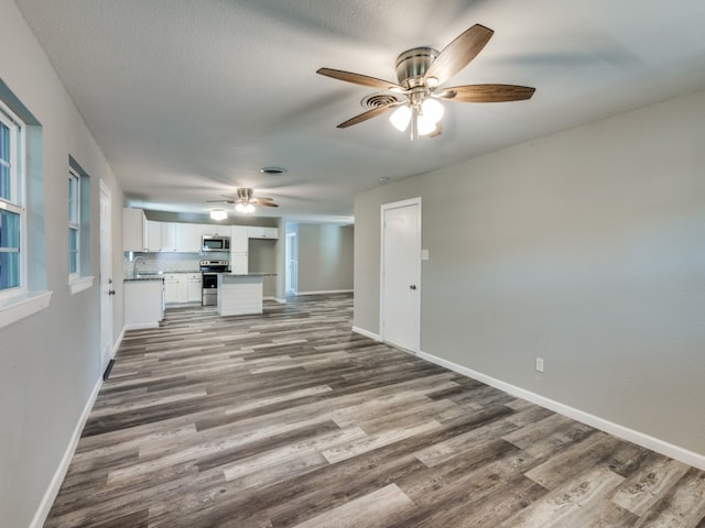 unfurnished living room featuring hardwood / wood-style floors, sink, and ceiling fan