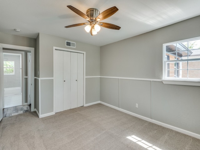 unfurnished bedroom featuring ceiling fan, a closet, and light carpet