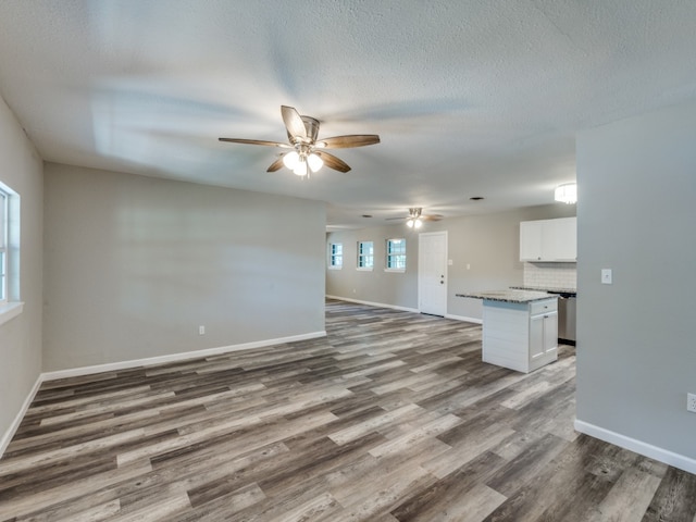 unfurnished living room with ceiling fan, a textured ceiling, and dark hardwood / wood-style floors