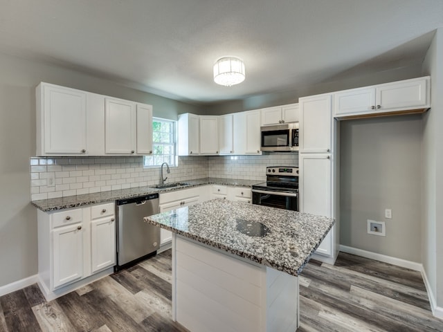 kitchen featuring light stone counters, appliances with stainless steel finishes, white cabinetry, and a kitchen island