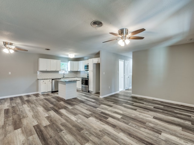 kitchen featuring light wood-type flooring, a kitchen island, stainless steel appliances, sink, and white cabinetry