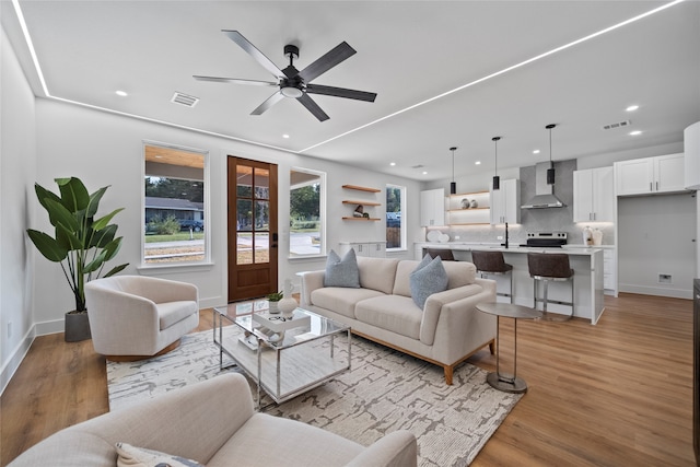 living room with ceiling fan, sink, and light hardwood / wood-style flooring