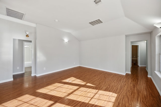 empty room with vaulted ceiling, wood finished floors, and visible vents