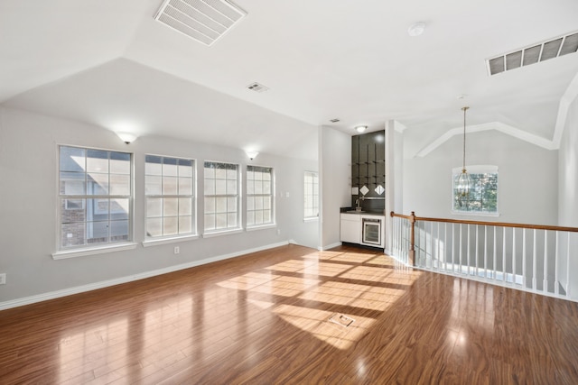 unfurnished room featuring visible vents, wood finished floors, and vaulted ceiling