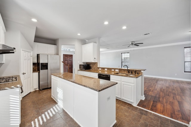 kitchen with tasteful backsplash, a kitchen island, appliances with stainless steel finishes, a peninsula, and a sink