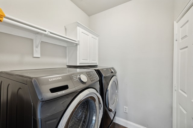 washroom with baseboards, cabinet space, and washing machine and dryer