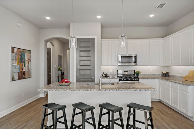 kitchen featuring a center island with sink, light hardwood / wood-style floors, white cabinetry, and stainless steel appliances