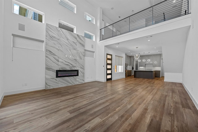 unfurnished living room featuring hardwood / wood-style flooring, a fireplace, and a towering ceiling