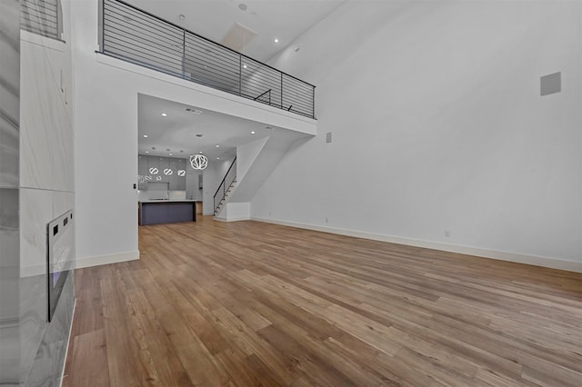 unfurnished living room with a high ceiling and light hardwood / wood-style flooring