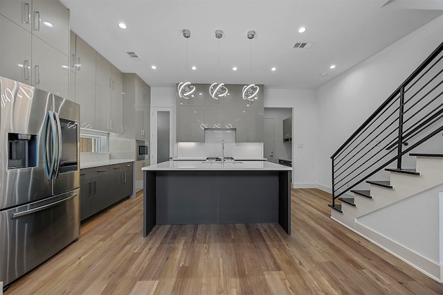 kitchen featuring appliances with stainless steel finishes, gray cabinets, decorative light fixtures, and light hardwood / wood-style floors