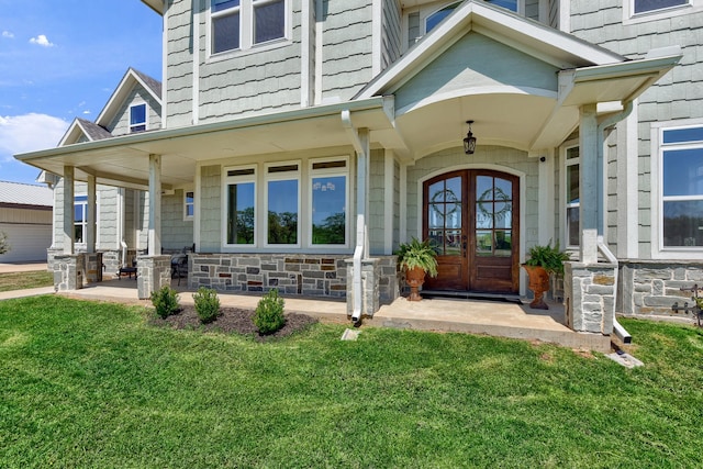 doorway to property featuring french doors, a yard, and covered porch