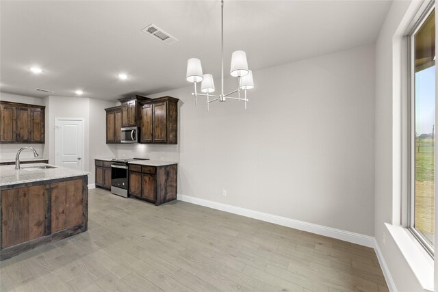 kitchen featuring appliances with stainless steel finishes, pendant lighting, sink, light stone counters, and dark brown cabinets