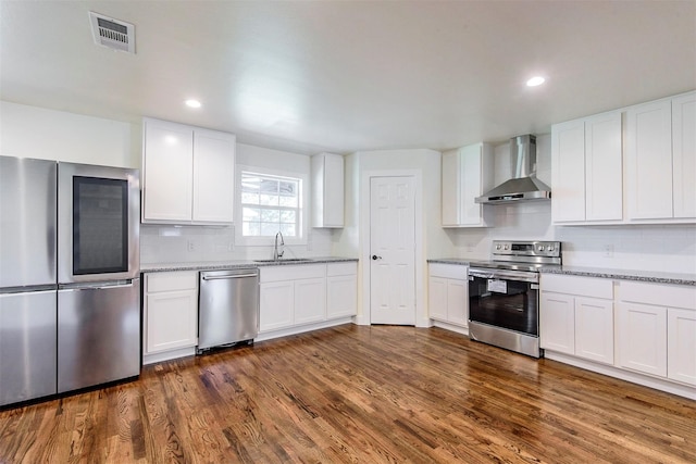 kitchen featuring wall chimney range hood, white cabinets, appliances with stainless steel finishes, and dark hardwood / wood-style floors