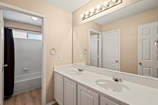 bathroom featuring shower / tub combo with curtain, hardwood / wood-style flooring, vanity, and a textured ceiling