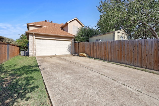 view of side of property with a garage, a yard, and central AC