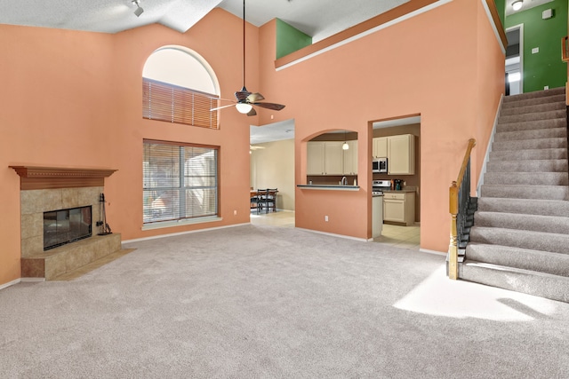 unfurnished living room with ceiling fan, high vaulted ceiling, light colored carpet, and a healthy amount of sunlight