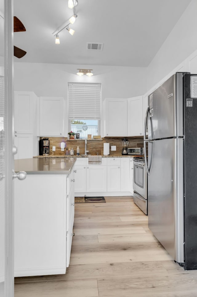 kitchen featuring light hardwood / wood-style floors, appliances with stainless steel finishes, backsplash, and white cabinetry