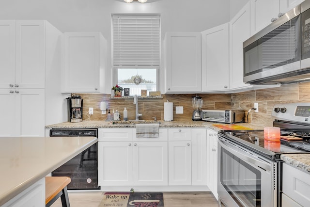 kitchen featuring sink, light hardwood / wood-style flooring, backsplash, white cabinetry, and appliances with stainless steel finishes