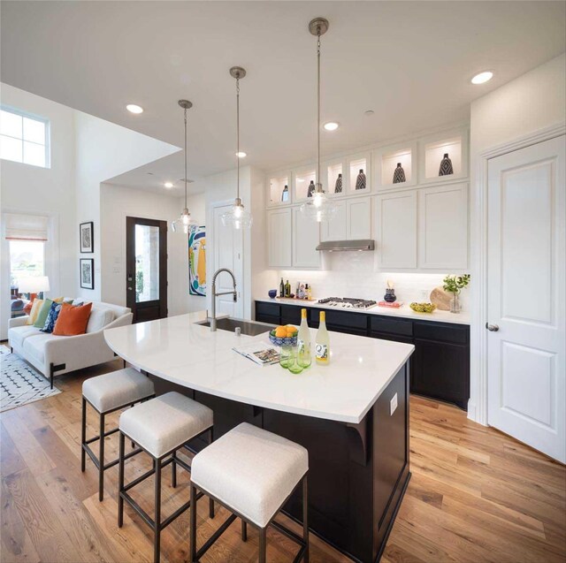 kitchen featuring white cabinets, a center island with sink, light wood-type flooring, and sink