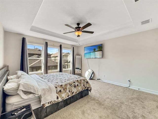 carpeted bedroom featuring ceiling fan and a raised ceiling