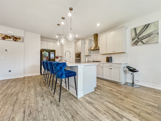 kitchen featuring white cabinets, light hardwood / wood-style flooring, hanging light fixtures, and wall chimney range hood