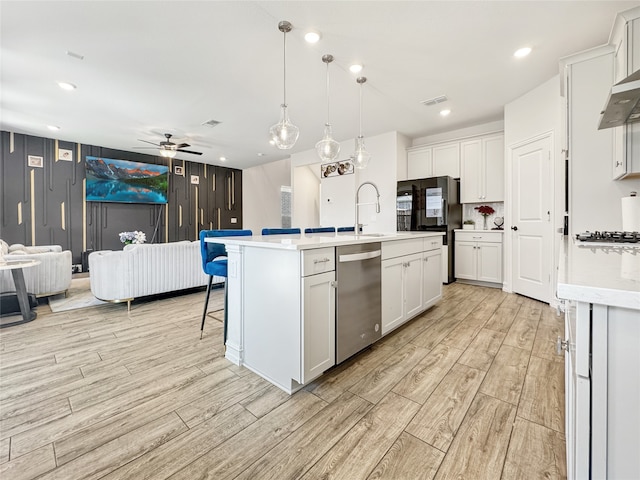 kitchen featuring dishwasher, an island with sink, and white cabinetry